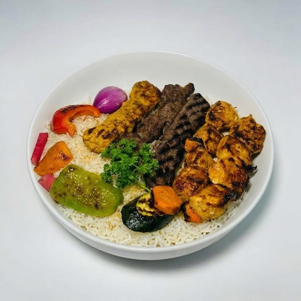 A white bowl filled with rice, various grilled meats, and colorful grilled vegetables.